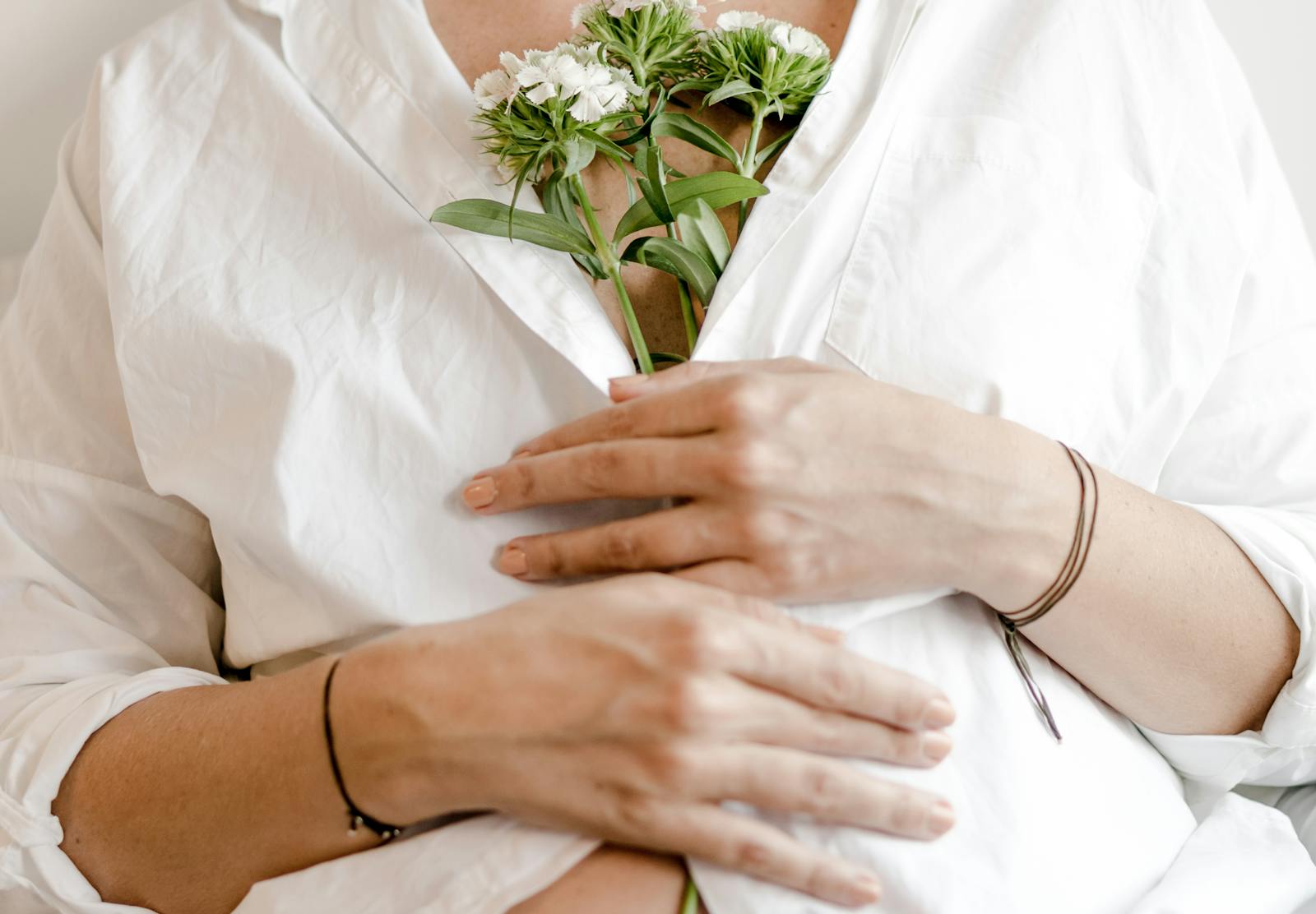 A peaceful image of a woman in white holding flowers, symbolizing maternity and tranquility.
